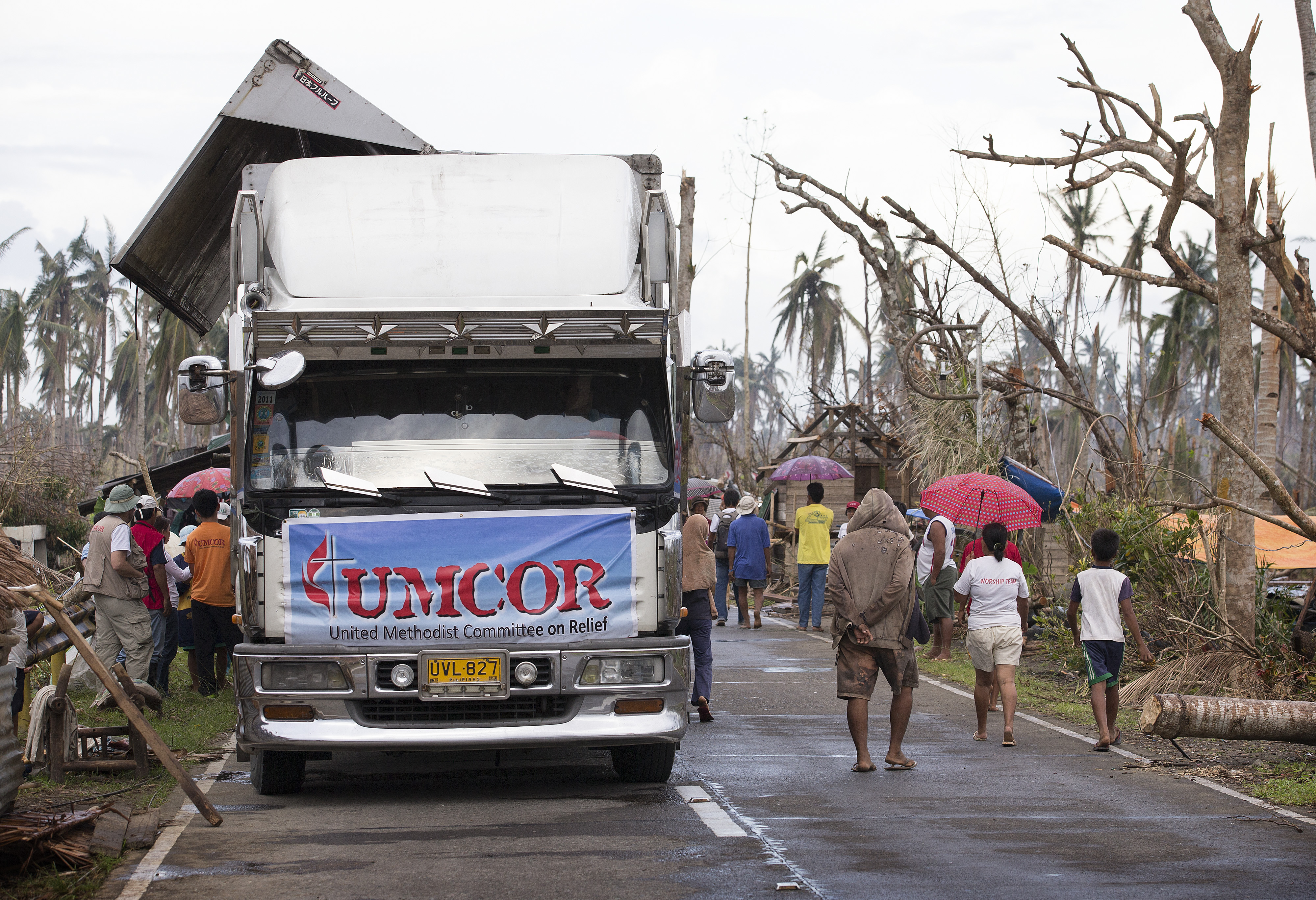 Membros da comunidade passam por um local de distribuição de alimentos para o Comitê Metodista Unido de Alívio após o tufão Haiyan em Dagami, Filipinas. Foto por Mike DuBose, Notícias MU.