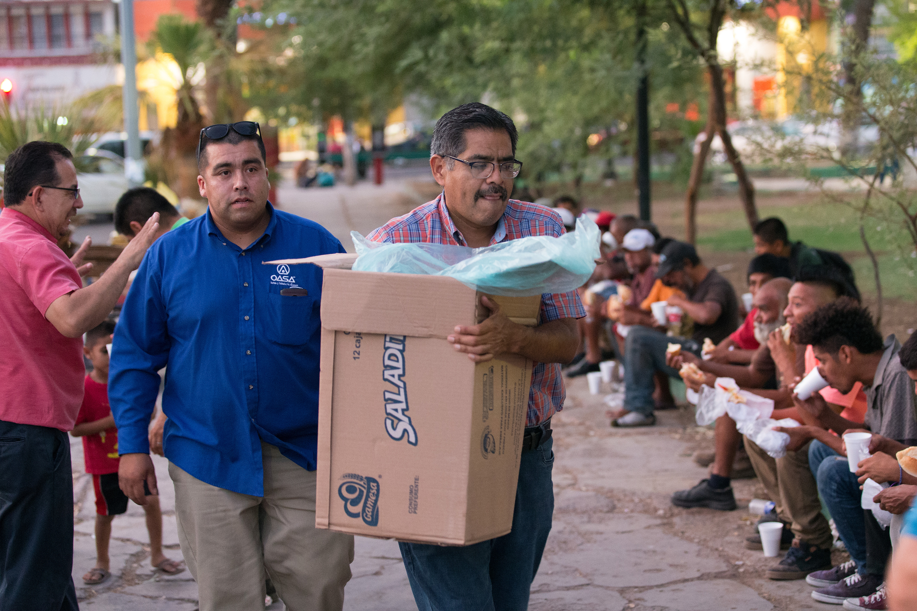 Bishop Felipe Ruiz Aguilar of the Methodist Church of Mexico (front) and Roberto Casares of El Divino Redentor Methodist Church help serve dinner to migrants and others living on the street at Mariachi Plaza in Mexicali, Mexico, in August 2018. Ruiz was among six bishops of the Methodist Church of Mexico who signed a statement urging better treatment of refugees. File photo by Mike DuBose, UMNS.