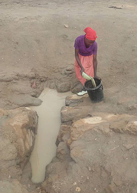 Gogo Felistas Washaya fetches water at the drying Nyamacheni Dam in Gokwe, Zimbabwe. Humans and livestock are using the same source of water in this area plagued by persistent drought. Photo by Kudzai Chingwe, UM News.