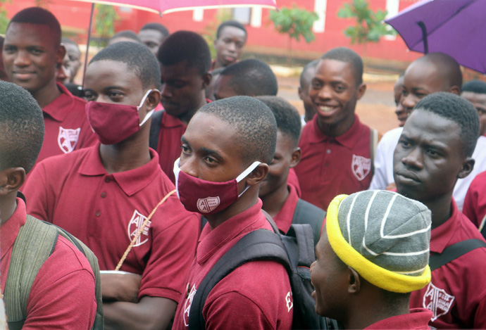 Os alunos da Academia Albert da Metodista Unida em Freetown, Serra Leoa, escutam o Director Junisa Vandy enquanto ele explica as directrizes para os Exames de Certificação da Escola Sénior da África Ocidental. Os alunos, como muitos em outros lugares em locais públicos em Serra Leoa, ainda não se adaptaram totalmente ao uso de máscaras. Foto de Phileas Jusu, Noticias MU.