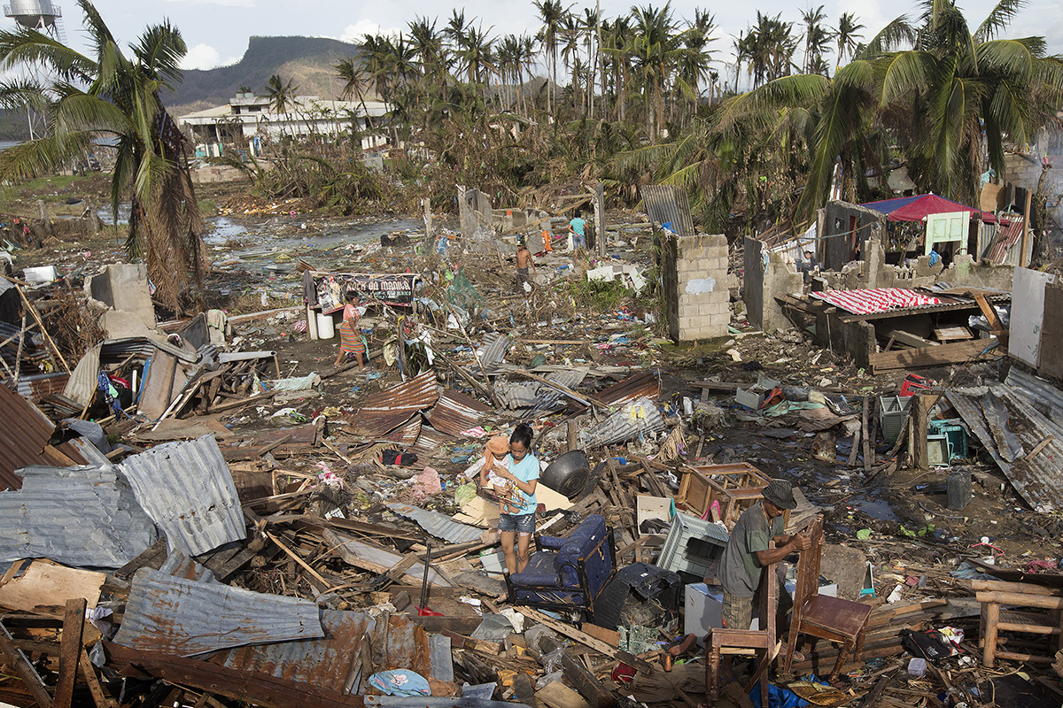 Supervivientes del tifón Haiyan recogen los escombros acumulados por la tormenta en Tacloban, Filipinas en 2013, mientras buscan sus posesiones perdidas. Jóvenes metodistas de todo el mundo están trabajando juntos/as para luchar contra el calentamiento global y se han centrado en equipar a las comunidades vulnerables en la primera línea del cambio climático, con los recursos que necesitan para adaptarse al mundo cambiante. Foto de archivo de Mike DuBose, Noticias MU.