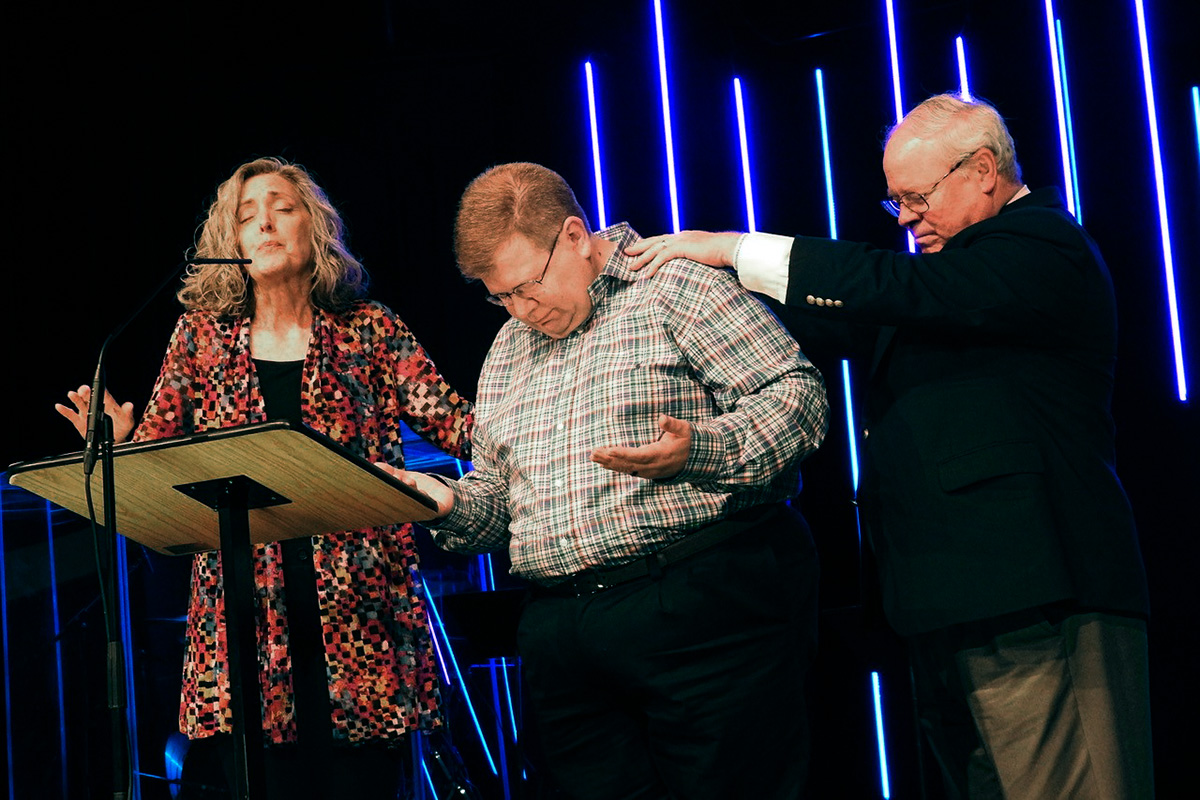 The Revs. Carolyn Moore and Keith Boyette pray for the Rev. Jay Therrell (center) at the Wesleyan Covenant Association’s May 7 gathering in Avon, Ind. The day before, the WCA’s Global Legislative Assembly elected Therrell as the new WCA president. He’ll succeed Boyette, who will be top executive of the new Global Methodist Church. Photo by Sam Hodges, UM News.