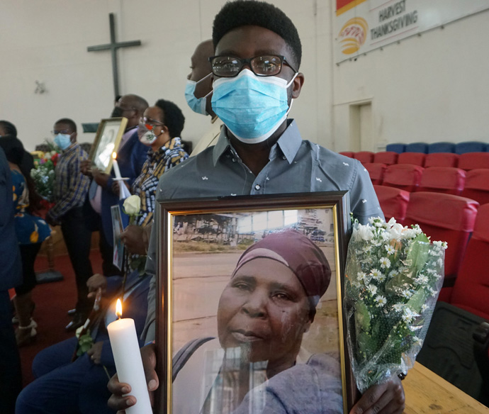 Ale White holds a picture of his mother, Sarah Kaukonde, a candle and flowers honoring her during a memorial service at Chisipiti United Methodist Church in Zimbabwe. United Methodist churches in Zimbabwe offered closure to grieving families and church members who may not have been able to attend funerals or had loved ones buried by special health personnel. Photo by Kudzai Chingwe, UM News.
