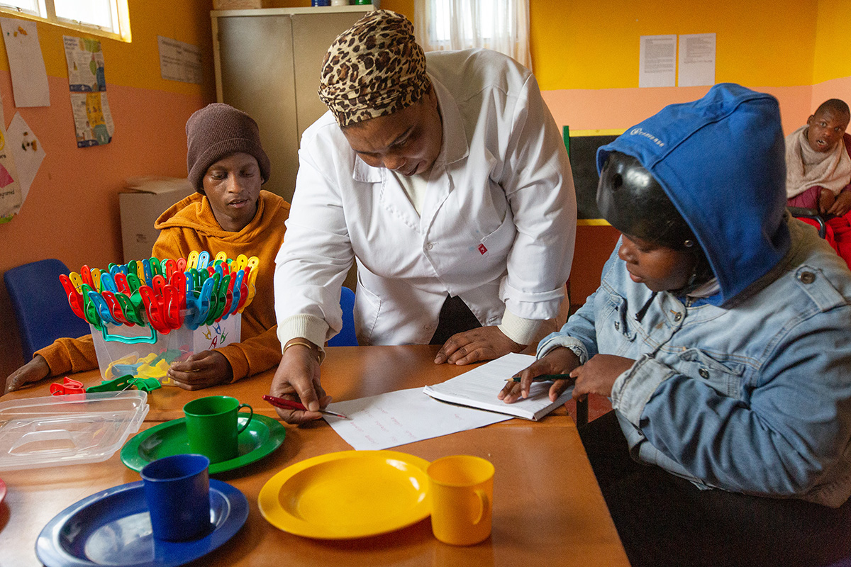 La maestra Thembakazi Bojana trabaja con estudiantes en el Centro Infantil Nomaxabiso en el vecindario Philippi East de Ciudad del Cabo, Sudáfrica. El centro, que recibe apoyo de La Iglesia Metodista Unida, atiende a niños/as con necesidades educativas especiales. Foto de Mike DuBose, Noticias MU.