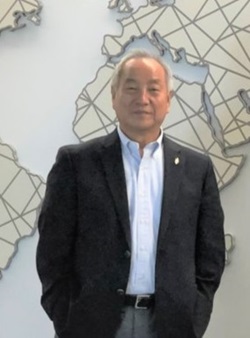 정희수 감독이 2022년 9월 29일 한인목회강화협의회 연례 회의 중 “모든 곳에서 모든 곳으로”라는 세계선교부 구호와 세계지도가 붙여진 세계선교부 사무실 앞에 서 있다. 사진, 김응선 목사, 연합감리교뉴스.