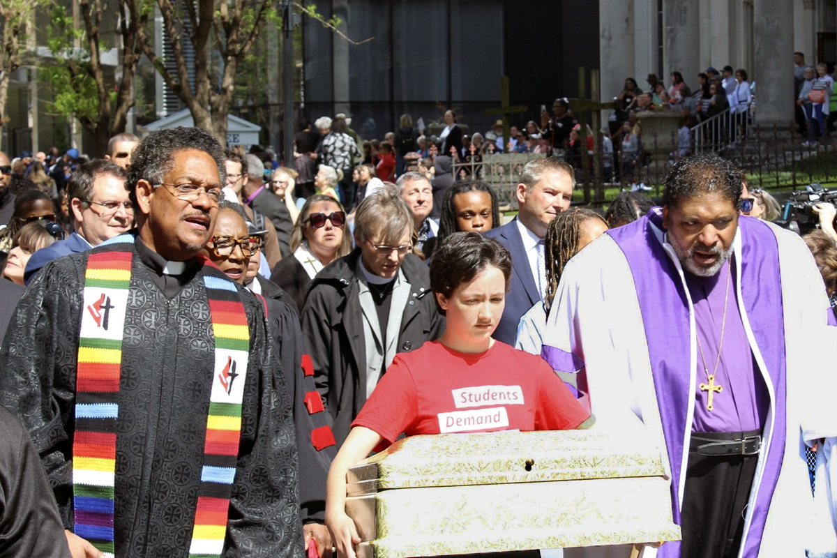 El Rev. Stephen Handy a la izquierda, pastor de la Iglesia Metodista Unida McKendree y el Rev. William Barber II a la derecha se unen a Shannon Felder mientras lleva el ataúd de un niño durante una marcha el 17 de abril en Nashville, Tennessee para protestar contra la violencia armada e impulsar una legislación sobre control de armas. Se llevaron cinco ataúdes y una urna desde la Iglesia Metodista Unida McKendree hasta el Capitolio del Estado de Tennessee, uno por cada víctima del tiroteo en la escuela del 27 de marzo en Nashville. Foto de Vernon Jordan, Noticias MU.