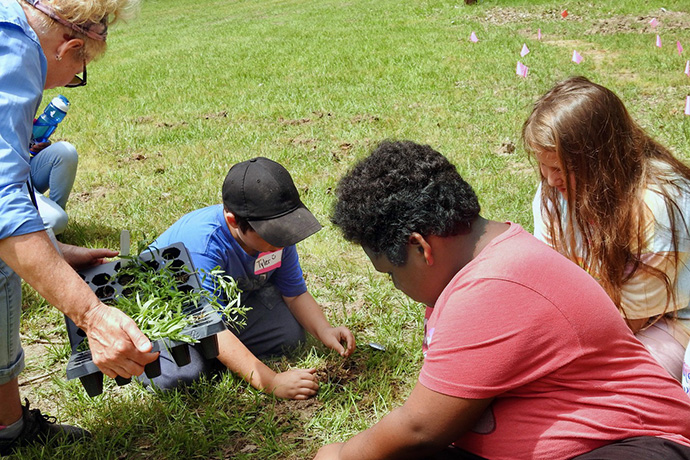 Children attending a Cultiv8 Community camp on May 19 plant milkweed, a wildflower depended on by monarch butterflies. This spring and summer, the nonprofit has brought about 800 kids from the Paris, Texas, area to the nearby Methodist Camp on Pat Mayse Lake for time in nature. Photo by Sam Hodges, UM News.