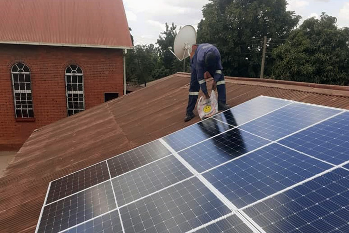 Munashe Bhero checks on the solar system he installed at St. Paul United Methodist Church in Harare, Zimbabwe. Bhero attends a different United Methodist church but got the job through the church’s WhatsApp business group, which connects church members around the region. Photo by Priscilla Muzerengwa, UM News.