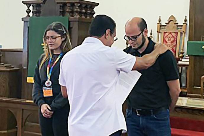 El Obispo Héctor Burgos, líder episcopal de la Conferencia Anual del Norte de Nueva York y de MARCHA, ora por dos de los nuevos lideres electos/as en la plenaria, durante el culto de clausura de la reunión De izquierda a derecha: Karián Natal-Serrano, Iglesia Metodista de Puerto Rico, Obispo Héctor Burgos y José Contreras, laico de la Jurisdicción Sur Central.