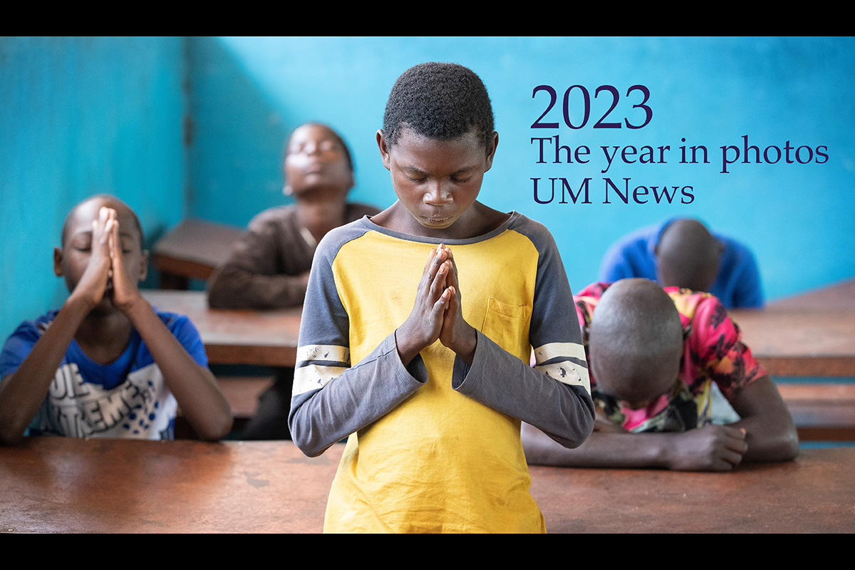 Acima: Adriano António Paulino (em pé) junta-se em oração antes do almoço na Missão Metodista Unida de Quéssua em Angola. Um programa de alimentação atende até 700 crianças das vilas circunvizinhas. Foto de Mike DuBose, Notícias da UM.