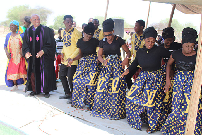 L’évêque Eben K. Nhiwatiwa (en robe) danse avec les membres de la chorale du poste de prédication de l’Église Méthodiste Unie au camp de réfugiés de Tongogara. Photo de Kudzai Chingwe, UM News.