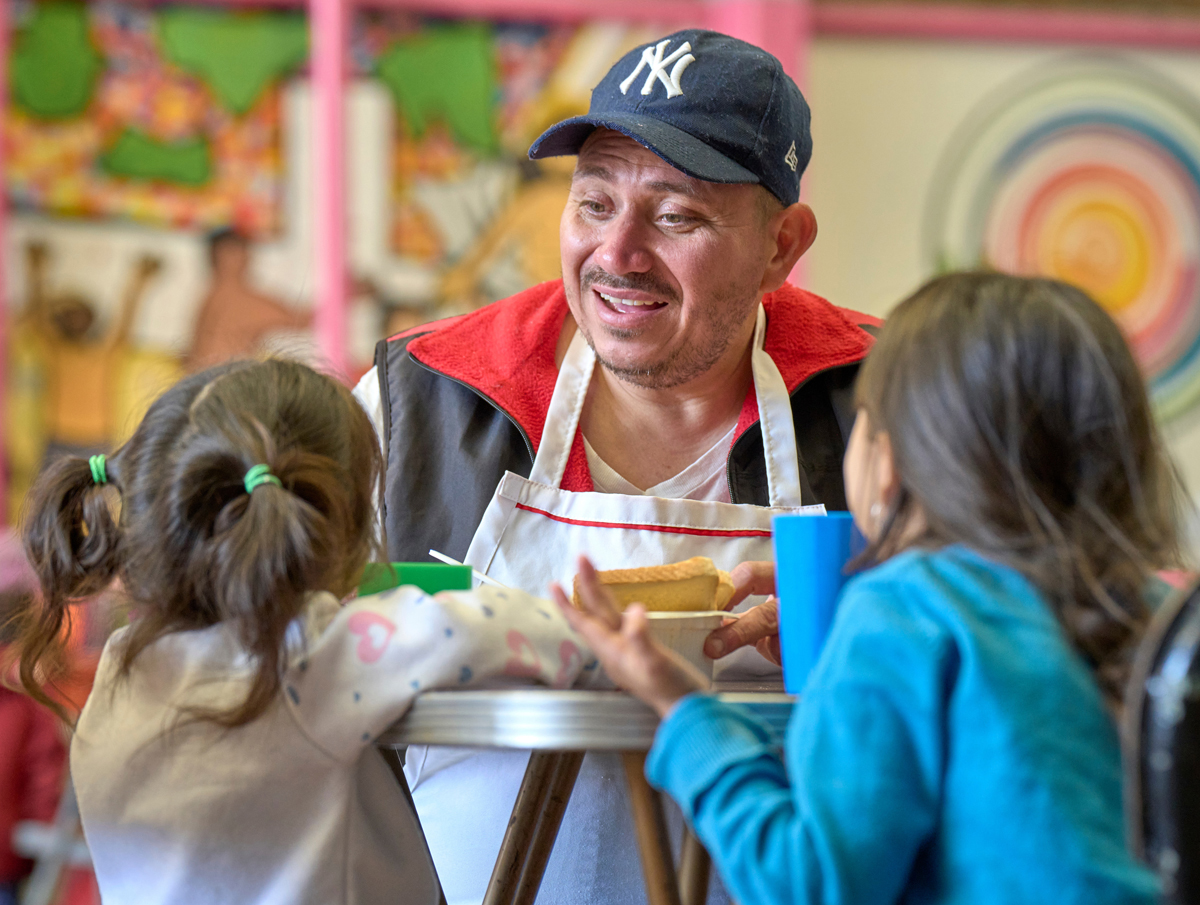 Victor Lugo, a migrant from Venezuela, talks with two of his granddaughters at CAFEMIN, a migrant shelter in Mexico City. Founded by the Josephine Sisters, a Catholic religious order, the shelter has been overwhelmed in recent months by requests for shelter and other forms of assistance. Lugo, who volunteers in the shelter's kitchen, is traveling with seven family members, including the two girls. They are awaiting an appointment with Mexican immigration officials, hoping for a transit visa that will allow them to proceed further north. Photo by the Rev. Paul Jeffrey, UM News.