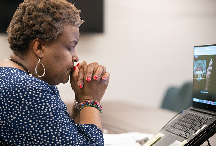 Tina Boone joins in prayer with callers on the phone and the congregation in the sanctuary at Gordon Memorial United Methodist Church in Nashville, Tenn., while hosting dial-in worship for remote participants who don’t have access to the church’s Facebook livestream. Photo by Mike DuBose, UM News.
