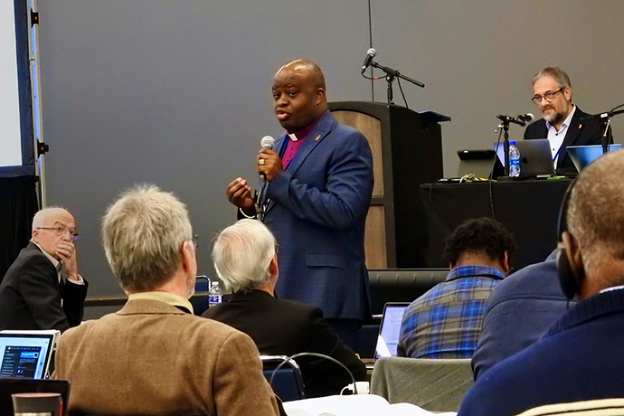 O Bispo Mande Muyombo dirige-se à Comissão Permanente sobre assuntos da Conferência Central durante uma reunião de 22 de abril em Charlotte, CN. O comitê reuniu-se pouco antes da Conferência Geral, decidindo se avançaria com petições relacionadas com o trabalho da denominação em África, Filipinas e Europa. Foto de Sam Hodges, Notícias MU.