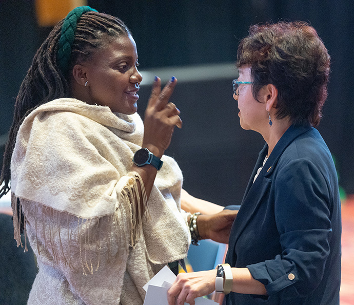 Juliet Nabukalu (à gauche) de la Conférence de l'Ouganda et du Sud-Soudan s'entretient avec Sung-ok Lee des Femmes Unies dans la Foi (United Women in Faith) lors d'une réunion d'information pour les délégués venant de l'extérieur des Etats-Unis, organisée avant la Conférence Générale Méthodiste Unie à Charlotte (Caroline du Nord). Photo par Mike DuBose, UM News.