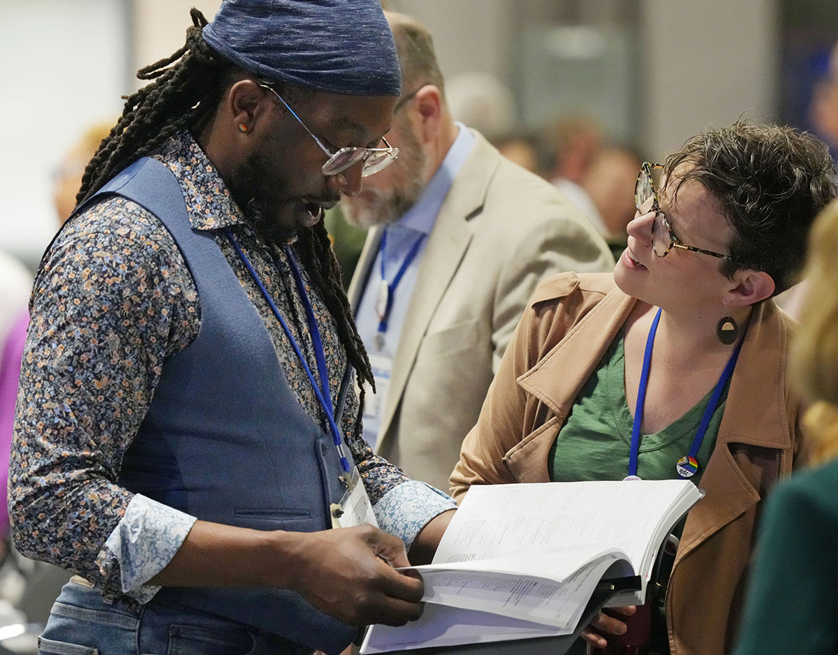 Delegates Jay Williams (left), New England Conference, and Allie Scott, Wisconsin Conference, look over the day’s agenda before the start of the United Methodist General Conference plenary session on April 30 in Charlotte, N.C. Photo by Larry McCormack, UM News.