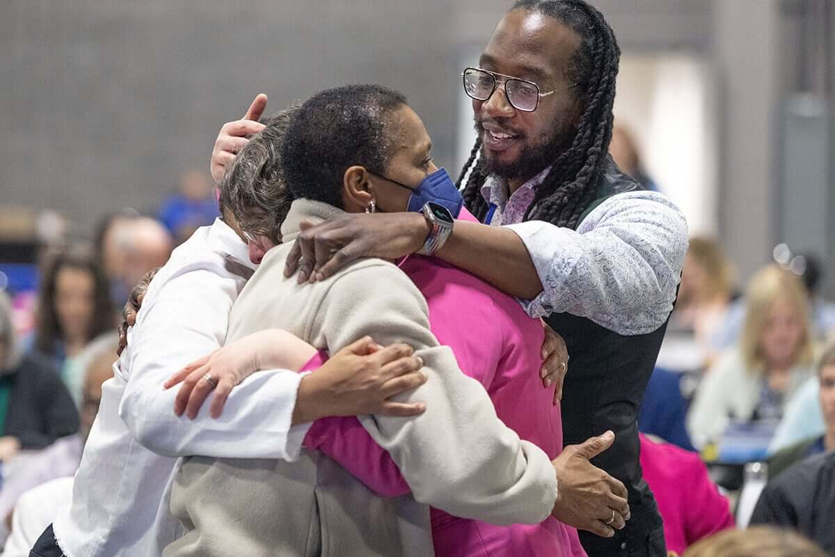 O Rev. Jay Williams (à direita) abraça os colegas delegados depois que a Conferência Geral Metodista Unida, reunida em Charlotte, Carolina do Norte., votou em 1º de maio para remover a proibição de longa data da Igreja Metodista Unida sobre a ordenação de clérigos que são "homossexuais praticantes declarados". Foto de Mike DuBose, Notícias MU.