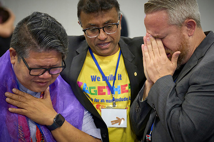 Izzy Alvaran (left), Scort Christy and Andy Oliver get emotional after General Conference delegates voted May 1 to remove the denomination’s ban on the ordination of clergy who are "self-avowed practicing homosexuals" — a prohibition that dated to 1984. The United Methodist Church’s legislative assembly is meeting in Charlotte, N.C., through May 3. Photo by Paul Jeffrey, UM News.