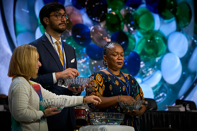 Lors d'un service commémoratif le 1er mai, des participants à la Conférence Générale Méthodiste Unie à Charlotte (Caroline du Nord) déposent des pierres dans un bol d'eau en souvenir des évêques, des conjoints et des délégués décédés depuis la dernière Conférence Générale. Photo par Paul Jeffrey, UM News.