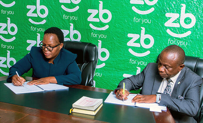 Letwin Mawire (left), ZB Life Assurance executive, and the Rev. Alan M. Gurupira, Zimbabwe Episcopal Area administrative assistant to the bishop, sign a landmark agreement for The United Methodist Church Cash Funeral Plan in Harare, Zimbabwe. Photo courtesy ZB Holdings Limited.