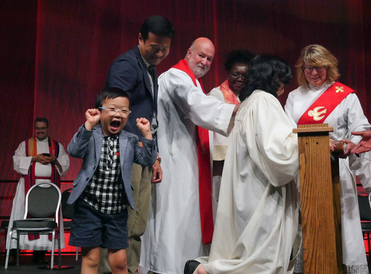 The Rev. Jee Hae Song’s son Joshua, 5, dances at her 2023 ordination during the Upper New York Annual Conference in Syracuse, N.Y. Song presented legislation to the 2024 Upper New York Annual Conference to enact a parental leave policy for United Methodists of Upper New York. The legislation would guarantee 13 paid weeks of leave for clergy and church workers whose family are expanding by birth, adoption or foster placement. Photo courtesy of the Upper New York Conference. 