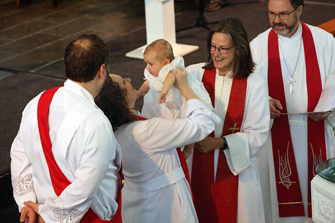 The Rev. Diane Kenaston holds her baby, Isaac, during his baptism at the 2019 West Virginia Annual Conference in Buckhannon, W.Va. Also pictured are (to her right) Bishop Sandra Steiner Ball; Kenaston’s husband, the Rev. Adam Ployd; and her father, the Rev. Joseph Kenaston. Photo courtesy of the Rev. Diane Kenaston.