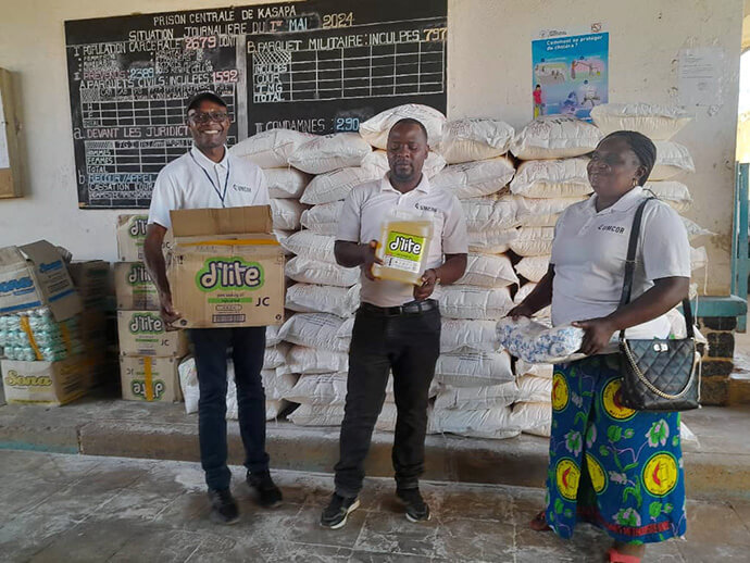 The Rev. Caleb Mbaz (left), coordinator of the Disaster Management Office for the South Congo Episcopal Area, carries a box containing vegetable oil for inmates at Kasapa Central Prison near Lubumbashi, Congo. Joining him are Disaster Management team members Kasongo Kilundu Olivier and Louise Tshiwengo. The United Methodist Church in Southern Congo distributed more than 16 tons of food and other supplies to the prison with support from the United Methodist Committee on Relief. Photo by Christian Kasweka, UM News.
