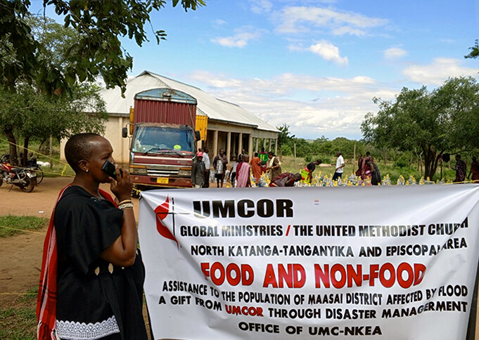 Local church pastor Paulina Koinasai of Kambala United Methodist Church in the Masai District holds a poster publicizing the distribution of food and non-food items to flood victims in the region. Photo courtesy of the North Katanga Episcopal Area disaster management office.