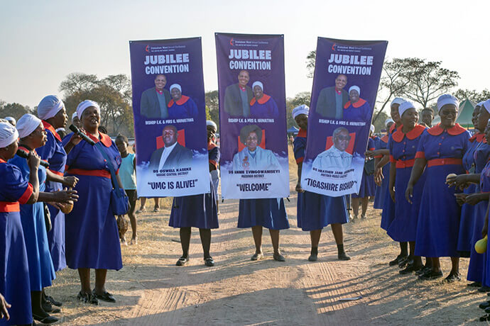 Des Femmes Méthodistes Unies du Zimbabwe accueillent l'évêque Eben K. Nhiwatiwa avec des bannières lors d'une convention jubilaire à Darwendale, au Zimbabwe, le 8 août. Les membres de Rukwadzano Rwe Wadzimai, l'organisation des femmes du pays, constituaient la majorité des participants, mais les hommes, les jeunes et les jeunes enfants faisaient également partie de la foule. Photo prise par Munyaradzi Matura.