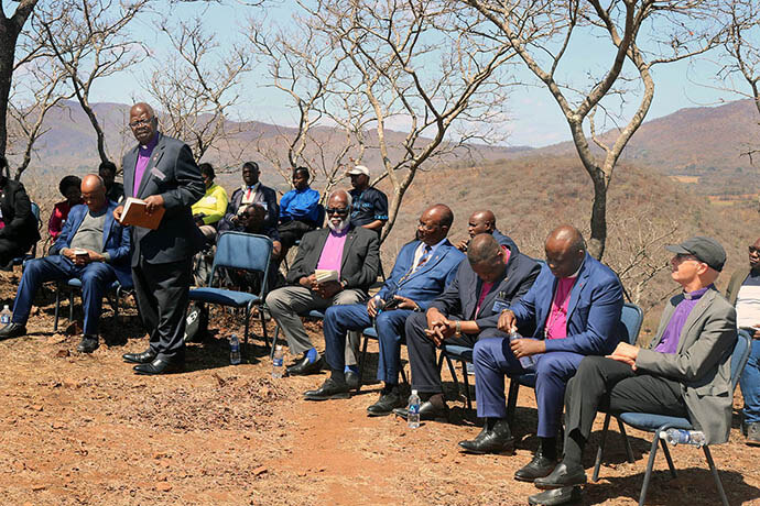 Retired Bishop David Yemba of Central Congo (standing) leads fellow bishops in a time of prayer and reflection on a mountain overlooking Africa University in Mutare, Zimbabwe. The Africa Colleges of Bishops held its annual retreat Sept. 2-5 at the United Methodist university. Photo by Eveline Chikwanah, UM News.