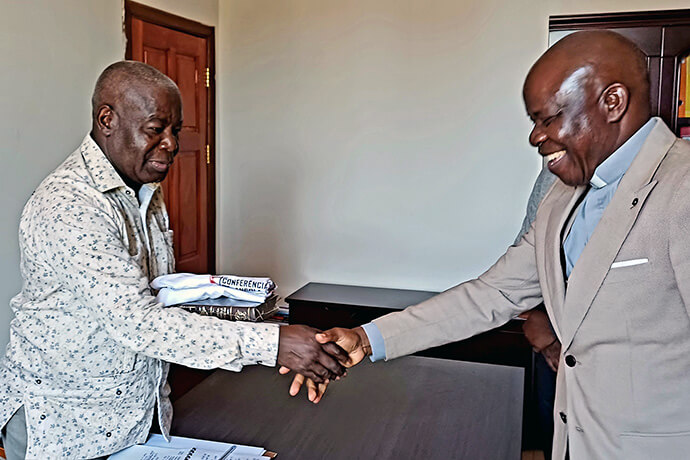 Superintendente Rogério Bartolomeu oferece uma Bíblia e uma camiseta do acampamento de evangelização ao Administrador de Luquembo. Luquembo, foto de João Nhanga.