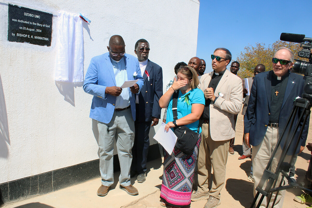 Amy Carmon, a member of Mary’s Chapel United Methodist Church in Bean Station, Tennessee, gets emotional during the dedication ceremony for Dzobo United Methodist Church in rural Zimbabwe. At left is the Rev. Samuel Dzobo, whose dream for a sanctuary in his home village inspired Mary’s Chapel to raise $48,000 to help build the church. At right is the Rev. Gerald Russell, a retired pastor in the Holston Conference and former United Methodist missionary. Photo by Kudzai Chingwe, UM News. 