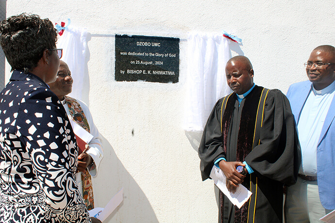 From left, the Revs. Alphistina Kanyandura, Alan Masimba Gurupira, Tendai Makono and Samuel Dzobo reveal a plaque dedicating Dzobo United Methodist Church on Aug. 25. The dream for a new sanctuary started with a dollar donation from the late Jo Hatfield of Mary’s Chapel United Methodist Church in Bean Station, Tennessee. Photo by Kudzai Chingwe, UM News. 