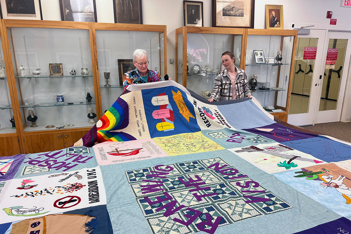Jan Lawrence (left), head of Reconciling Ministries Network, and Ashley Boggan D., top executive of the United Methodist Commission on Archives and History, hold up a Reconciling Congregations quilt during the Oct. 23 inauguration of The United Methodist Church’s new LGBTQ+ United Methodist Heritage Center in Madison, N.J. Photo by Crystal Caviness, courtesy of the Commission on Archives and History Facebook page.