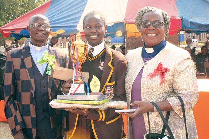 The Revs. Marcus and Faith Nyagato pose with student Nyasha Chabvondora, who won the top award for her grade at Seke 1 High School in Chitungwiza, Zimbabwe. The United Methodist clergy couple helped provide trophies for the school’s awards day. Photo by Kudzai Chingwe, UM News.