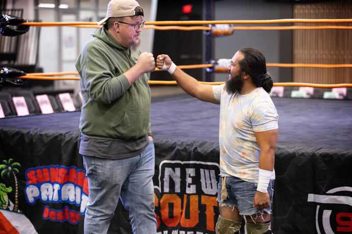 El Rev. Steven Barber a la izquierda, choca los puños con el luchador profesional Cabana Man Dan antes de su combate el 2 de noviembre en el Centro de Eventos de Priceville, Alabama. Barber, un pastor local metodista unido con licencia, se desempeña 