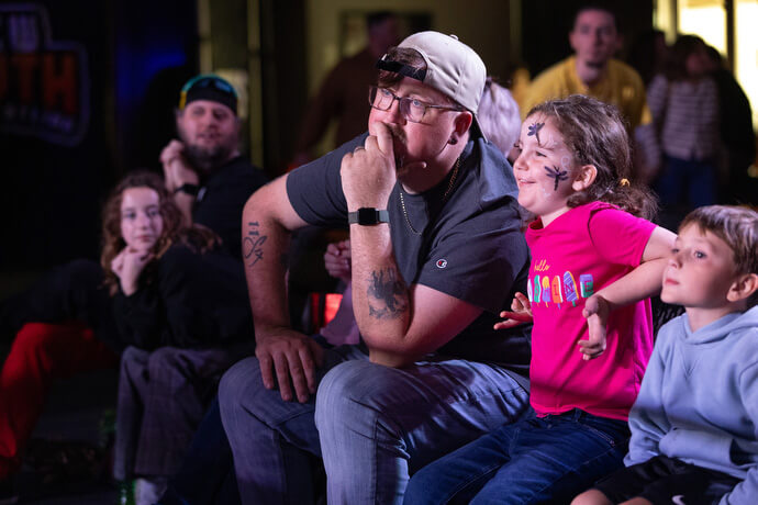 El Rev. Steven Barber al centro con su hija, Gwenivere, observan la acción durante un evento de New South Pro Wrestling en el Centro de Eventos de Priceville, Alabama. 