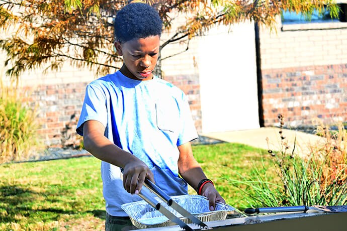 A young member of The Village United Methodist Church in DeSoto, Texas, helps out at the grill Oct. 27 in the church parking lot. The church works to mentor its youth by having them learn skills from the adult members of the congregation. Photo by Jim Patterson, UM News.