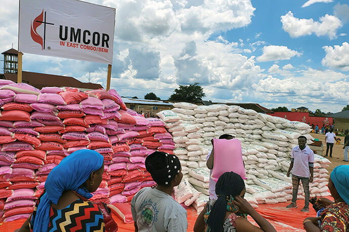 Des femmes font la queue devant des sacs de farine et de riz lors d'une distribution d'aide à Beni, au Congo. UMCOR, l'organisation de secours et de développement de l'Église Méthodiste Unie, a déboursé 150 000 dollars pour acheter de la nourriture et d'autres fournitures pour les personnes déplacées. Photo avec l'aimable autorisation du bureau de gestion des catastrophes de la Région Épiscopale du Congo Est.