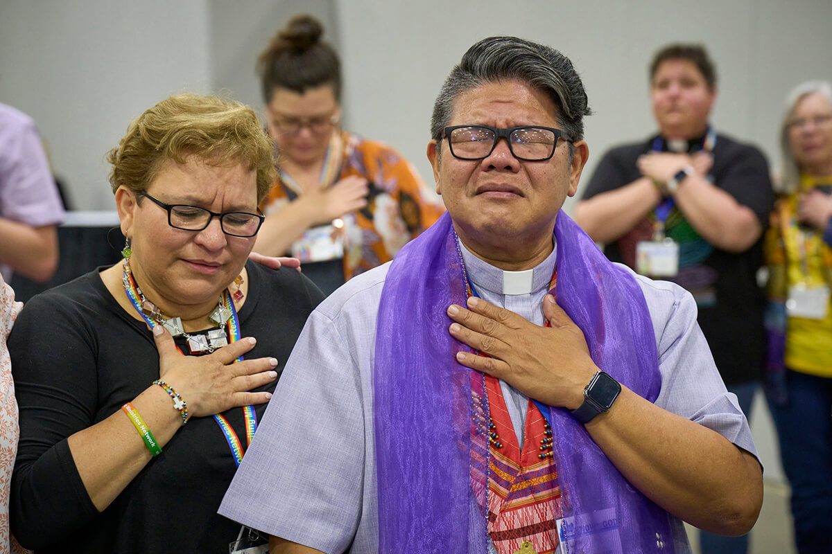 O Rev. Izzy Alvaran (à direita) e outros oram juntos em 1º de maio após a Conferência Geral Metodista Unida de 2024, reunida em Charlotte, NC, votar para remover a proibição da denominação sobre a ordenação de clérigos gays "praticantes declarados" — uma proibição que data de 1984. Alvaran está na equipe da Reconciling Ministries Network (Rede de Ministérios de Reconciliação), que revelou um novo plano estratégico após o sucesso na Conferência Geral do ano passado. Foto de arquivo de Paul Jeffrey, Notícias MU.