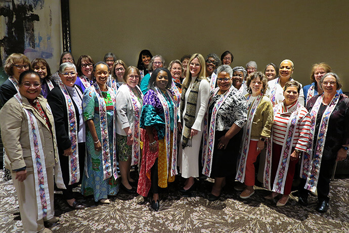 The Rev. Stephanie York Arnold (center), the new top executive of the United Methodist Commission on the Status and Role of Women, stands with 26 active and retired women bishops. York Arnold presented the bishops with stoles made by her mother. “I hope you will wear these when you serve communion, when you open the table wide for all to come and feast on the grace of our Savior,” York Arnold told the bishops. Photo by Heather Hahn, UM News.