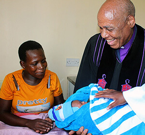 Bishop Eben K. Nhiwatiwa holds newborn Clarence Rinomhota as his mother, Sarah Mushamba, looks on at Chindenga rural health clinic in Mutoko, Zimbabwe. The center, which was dedicated Feb. 22, is the final clinic under the United Methodist Nyadire Mission Hospital to be renovated. Photo by Kudzai Chingwe, UM News.