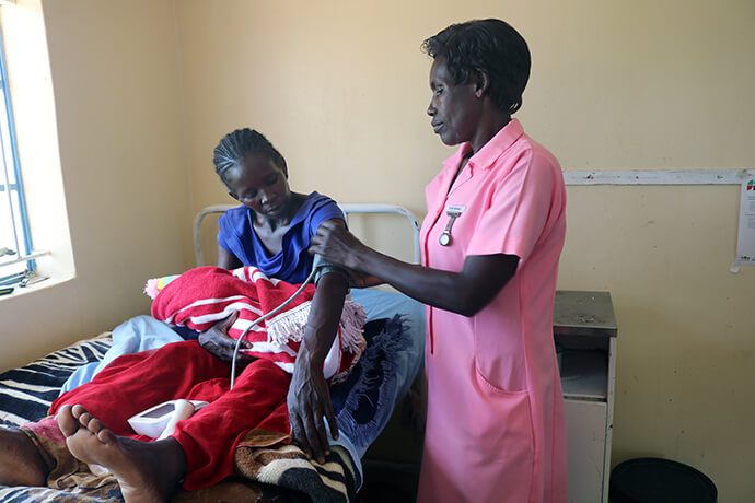 Esther Munhenga vérifie la tension artérielle et d'autres paramètres vitaux de Loveness Bhobho, 34 ans, environ une heure après son accouchement au centre de santé Mashambanhaka de l'Église Méthodiste Unie, situé à environ 80 km d'Harare, au Zimbabwe. C'est le quatrième bébé de Bhobho et le deuxième à naître dans cette clinique, l'une des six cliniques rurales revitalisées par des partenaires Méthodistes Unis, dont The Nyadire Connection et Global Ministries. Photo par Eveline Chikwanah, UM News.