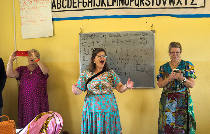 Amy Martin (au centre) enseigne une chanson aux élèves du Mama Lynn Center à Kindu, au Congo, lors d'une visite des membres des conférences du Tennessee-Western Kentucky et de Californie-Pacifique. Le révérend Birgitte French (à gauche) et Linda Boulos observent la scène. Grâce à des formations et à d'autres formes de soutien, le Mama Lynn Center aide les femmes du Congo à devenir économiquement indépendantes. Photo de Chadrack Tambwe Londe, UM News.
