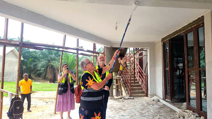 La révérende Birgitte French peint le balcon de la salle polyvalente Bishop Gabriel Yemba Unda au centre Mama Lynn à Kindu, au Congo. Mme French faisait partie d'une délégation américaine qui a visité les travaux de construction en cours au centre, qui a reçu le soutien financier des conférences Tennessee-Western Kentucky et California-Pacific de l'Église méthodiste unie. Photo de Chadrack Tambwe Londe, UM News.
