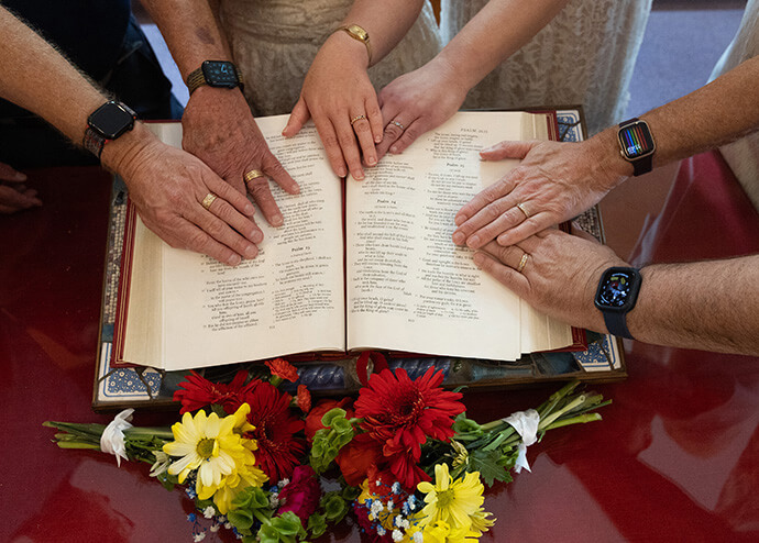 Three couples place their hands, adorned with wedding rings, on a Bible open to the Psalms following a service to renew their wedding vows at Edgehill United Methodist Church in Nashville, Tenn. Photo by Mike DuBose, UM News.