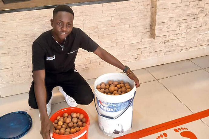 Africa University graduate Panashe Banda displays buckets of mazhanje, an African wild fruit, he brought as a gift to the Zimbabwe West Conference head office staff. Banda has been sharing his family’s harvest with the staff each year as a thank you for the church scholarship he received to attend the United Methodist university in Mutare, Zimbabwe. Photo by Chenayi Kumuterera, UM News.