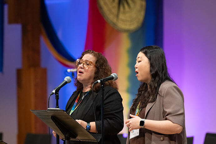 From left, the Revs. Lydia Muñoz and Sooah Na sing during Sunday service, which doubled as closing worship for the Reconciling Ministries Network convocation. Muñoz is the executive director of El Plan for Hispanic/Latine Ministry, and Na is an ordained elder in the Greater New Jersey Conference. Photo by Joscie Cutchens, UM News.   