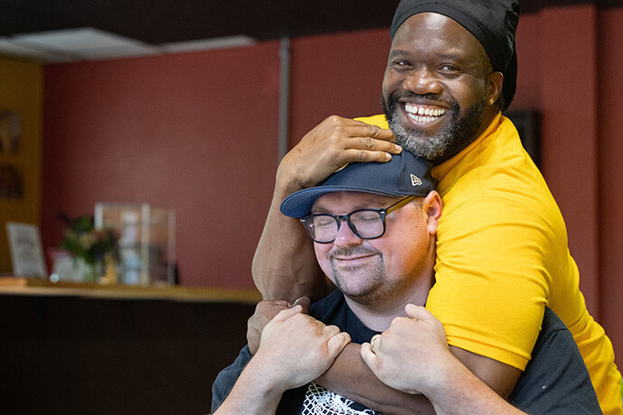 Timothy "GA" Underwood hugs the Rev. Dustin Mailman in the recently opened coffee shop of the Deep Time ministry in Asheville, N.C. Underwood serves as minister of social enterprise for Deep Time and Mailman is its founding pastor. The program, which seeks to create a spiritual community with people impacted by incarceration, is housed at Trinity United Methodist Church in Asheville.