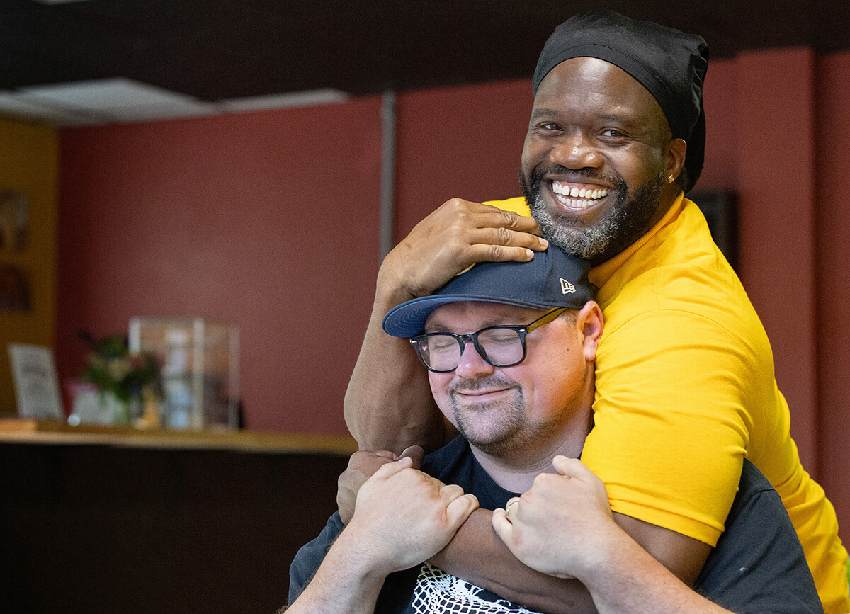 Timothy "GA" Underwood hugs the Rev. Dustin Mailman in the recently opened coffee shop of the Deep Time ministry in Asheville, N.C. Underwood serves as minister of social enterprise for Deep Time and Mailman is its founding pastor. The program, which seeks to create a spiritual community with people impacted by incarceration, is housed at Trinity United Methodist Church in Asheville.